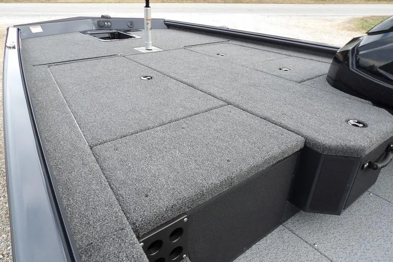 Slide: The Image of 2026 Lund 1875 Renegade boat deck with gray carpet and storage compartments. - 11