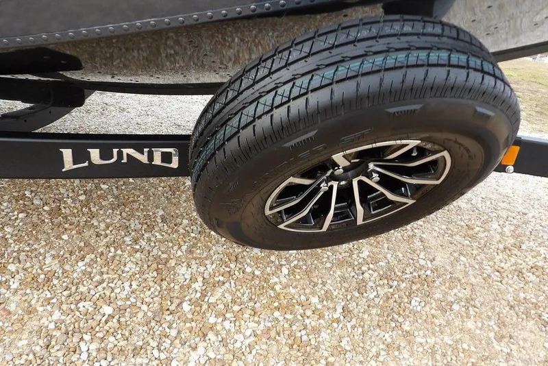 Slide: The Image of 2026 Lund 1875 Renegade trailer wheel on gravel surface. - 40