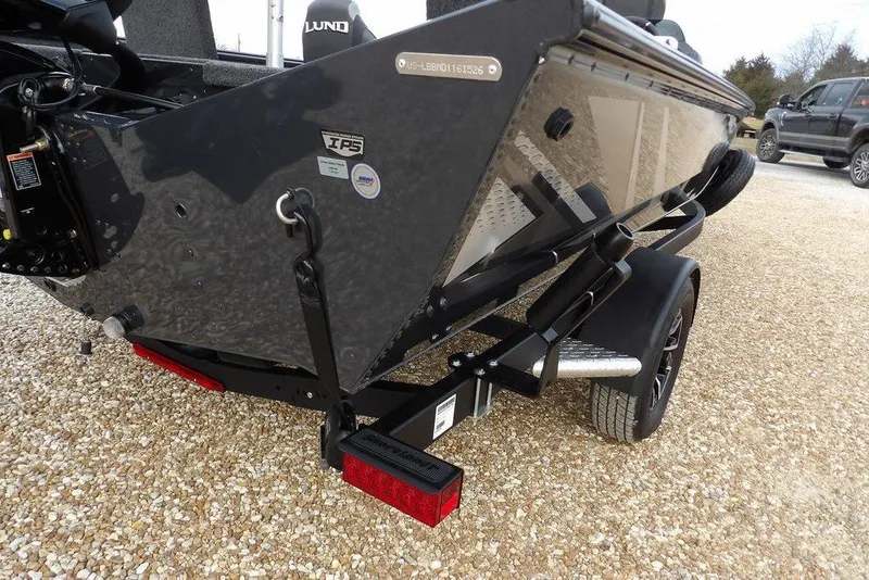 Slide: The Image of 2026 Lund 1875 Renegade boat on trailer, rear view, parked on gravel. - 46