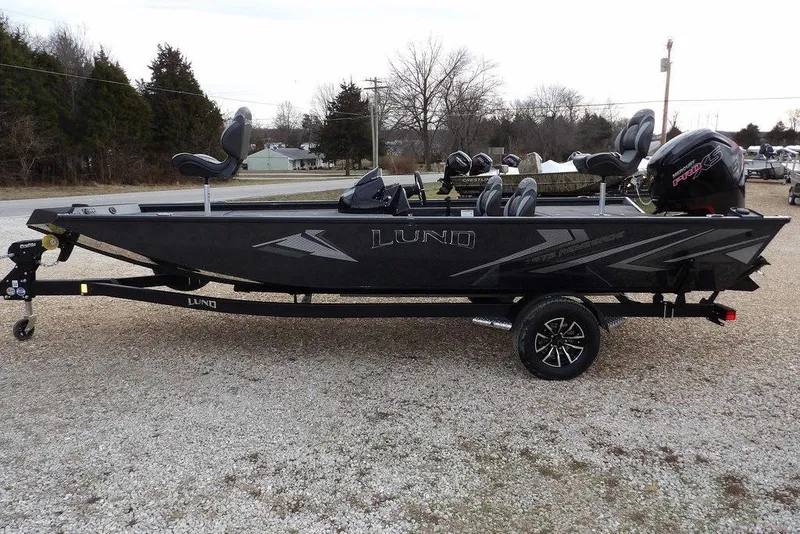 Slide: The Image of 2026 Lund 1875 Renegade fishing boat on trailer, sleek black design, parked outdoors. - 5
