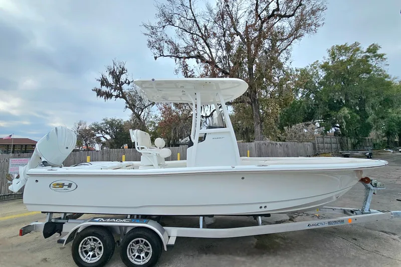 Slide: The Image of 2026 Sea Hunt BX 22 BR boat on trailer, parked outdoors with trees in background. - 8