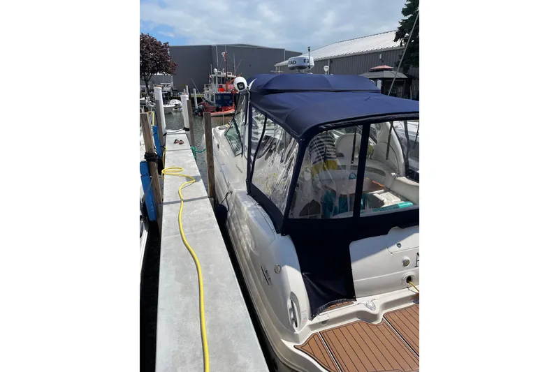 Slide: The Image of 2007 Sea Ray 340 Sundancer docked, featuring blue canopy and wooden deck. - 2