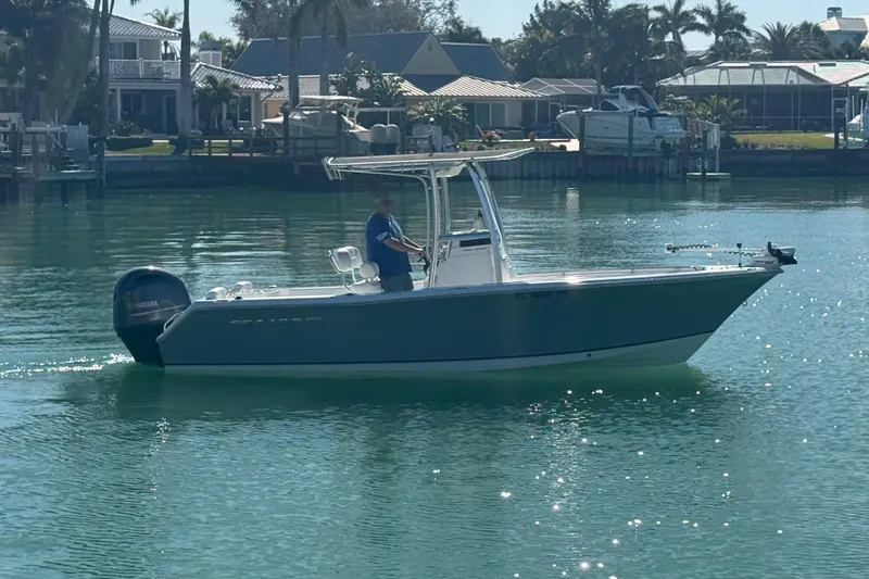 The Image of 2014 Sea Hunt Triton 220 boat on calm water near residential docks. - 0