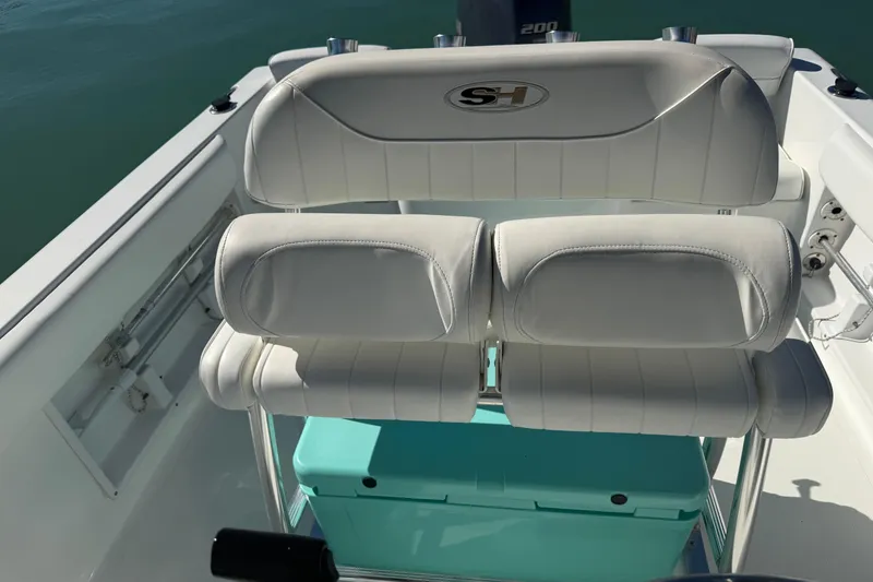 Slide: The Image of 2014 Sea Hunt Triton 220 boat interior with white cushioned seating and turquoise storage box. - 14