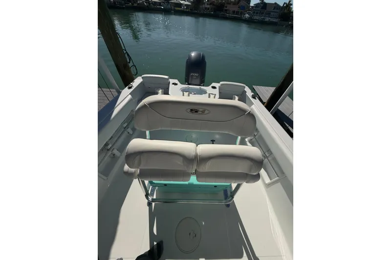 Slide: The Image of 2014 Sea Hunt Triton 220 boat interior with seating, overlooking calm waters. - 17