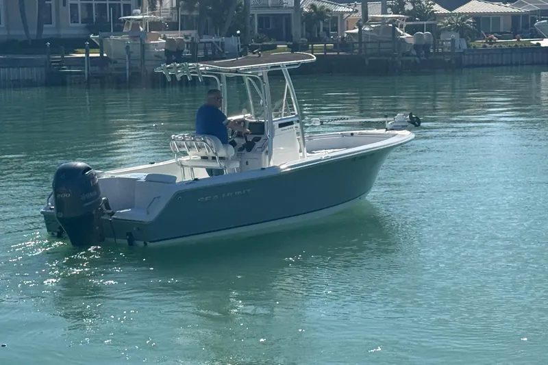 Slide: The Image of 2014 Sea Hunt Triton 220 boat on calm water near residential docks. - 2