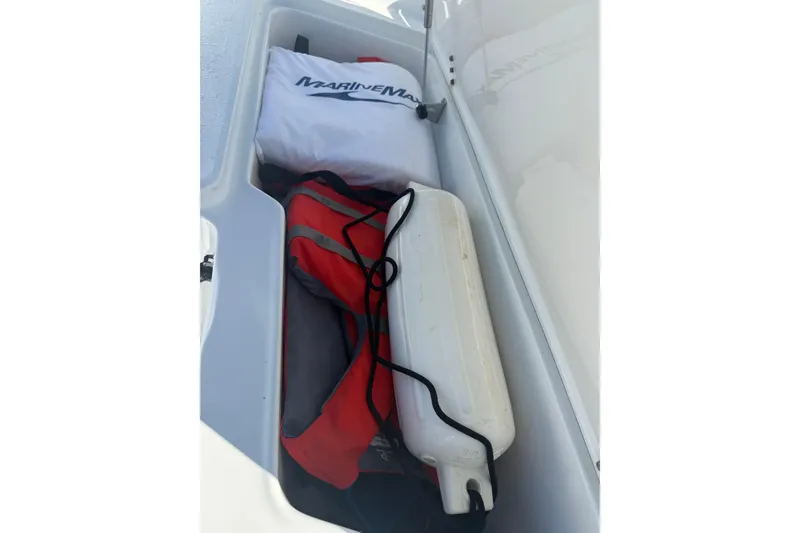 Slide: The Image of Storage compartment of 2014 Sea Hunt Triton 220 with life jacket and marine gear. - 22