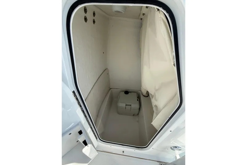 Slide: The Image of 2014 Sea Hunt Triton 220 boat interior storage compartment with curtain and portable toilet. - 32