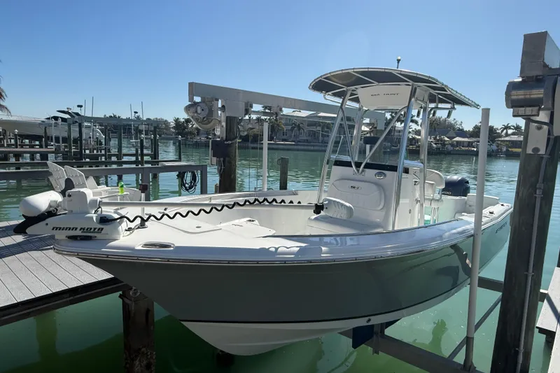Slide: The Image of 2014 Sea Hunt Triton 220 boat docked at a marina under clear blue skies. - 44