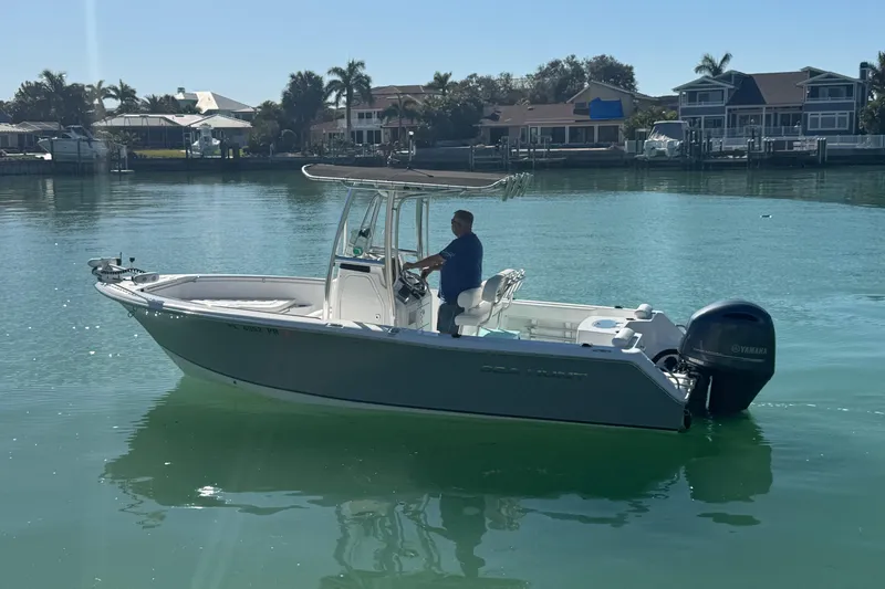 Slide: The Image of 2014 Sea Hunt Triton 220 boat on calm water, with a person steering. - 6