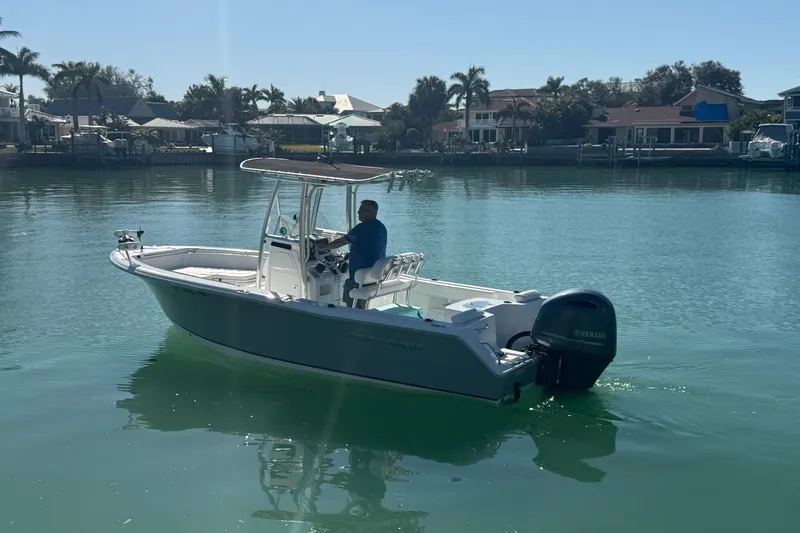 Slide: The Image of 2014 Sea Hunt Triton 220 boat on calm water with a person steering. - 7