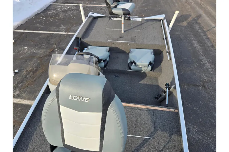 Slide: The Image of 2016 Lowe Skorpion boat interior with seating and steering wheel in a parking lot. - 17