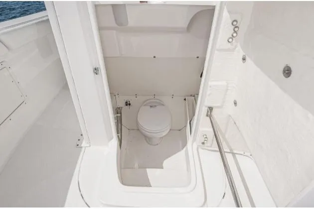 Slide: The Image of 2020 Robalo R272 Center Console boat interior with a compact marine toilet. - 11