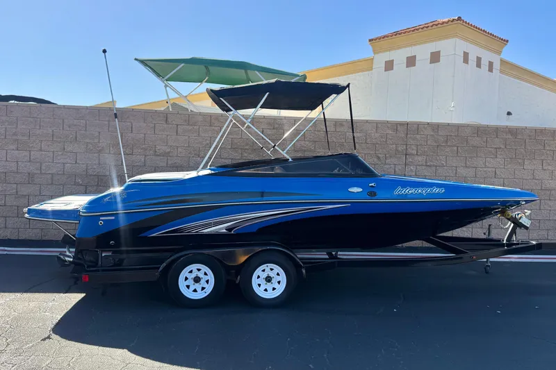 The Image of 2015 Caravelle 22 Interceptor boat on trailer, blue and black design, parked outdoors. - 0