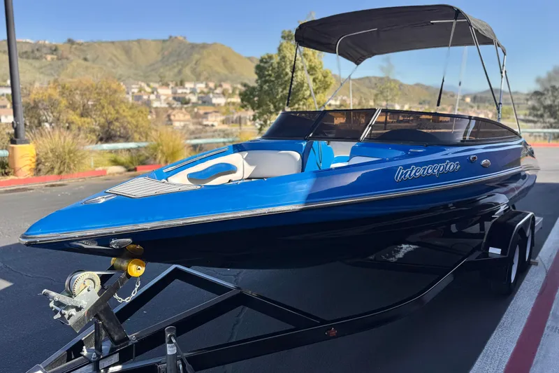 Slide: The Image of 2015 Caravelle 22 Interceptor boat on trailer, blue exterior, parked outdoors. - 3