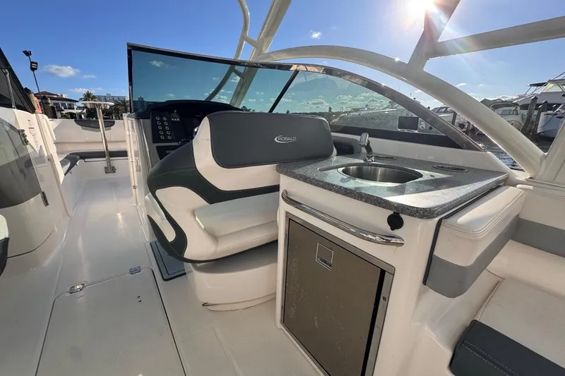 Slide: The Image of 2021 Robalo R317 Dual Console boat interior with seating and kitchenette under sunny sky. - 28