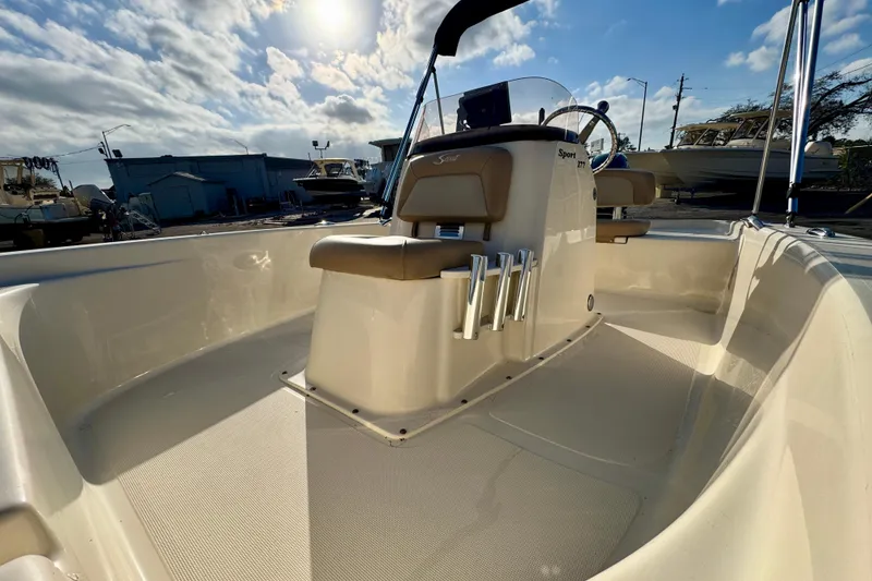 Slide: The Image of 2023 Scout 177 Sport boat interior with helm, rod holders, and seating under sunny sky. - 10