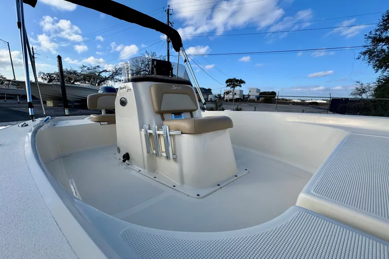 Slide: The Image of 2023 Scout 177 Sport boat interior with seating and console under blue sky. - 11
