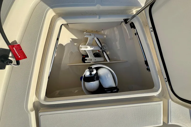 Slide: The Image of Open storage compartment on 2023 Scout 177 Sport boat with equipment inside. - 12