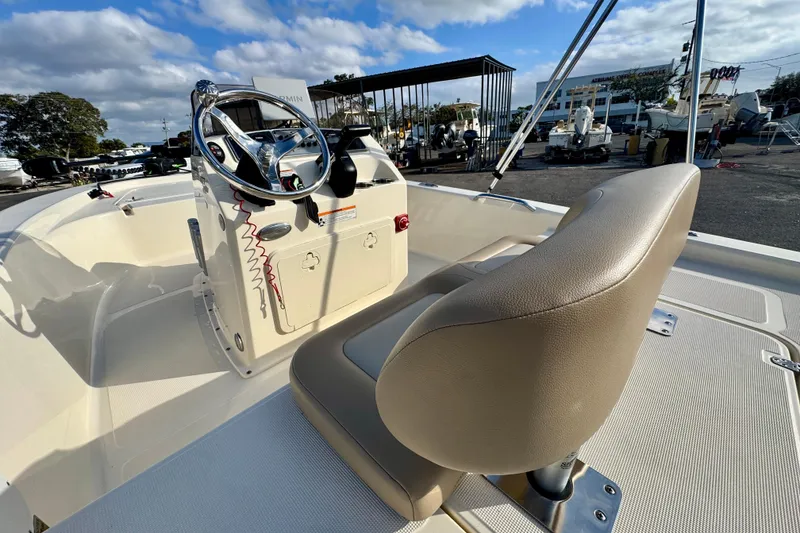 Slide: The Image of 2023 Scout 177 Sport boat interior with steering wheel and seating, under a partly cloudy sky. - 16