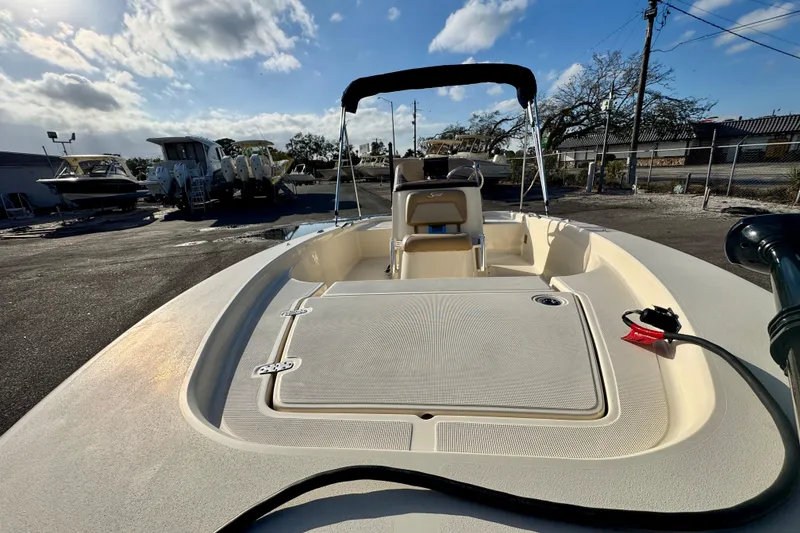 Slide: The Image of 2023 Scout 177 Sport boat with open deck, parked outdoors under a partly cloudy sky. - 9