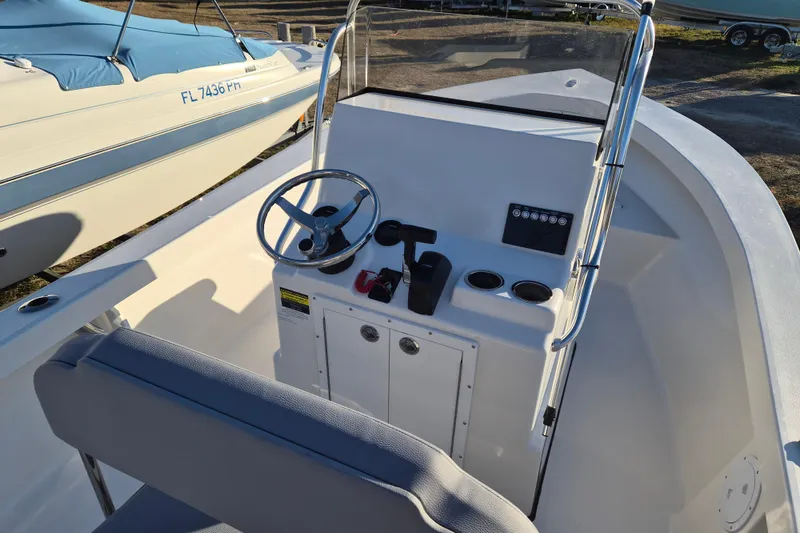 Slide: The Image of 2026 May-Craft 192 boat console with steering wheel and controls, docked beside another boat. - 6