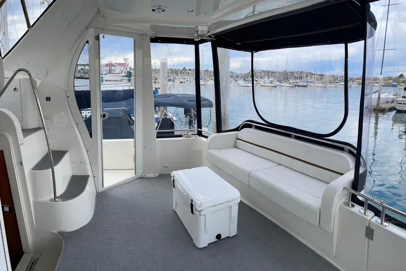 Slide: The Image of 2006 Carver 39 Motor Yacht interior with white seating, marina view, and stairs. - 5