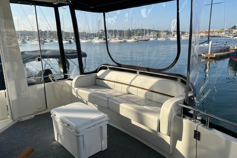 Slide: The Image of 2006 Carver 39 Motor Yacht interior with white seating, marina view, and clear windows. - 7