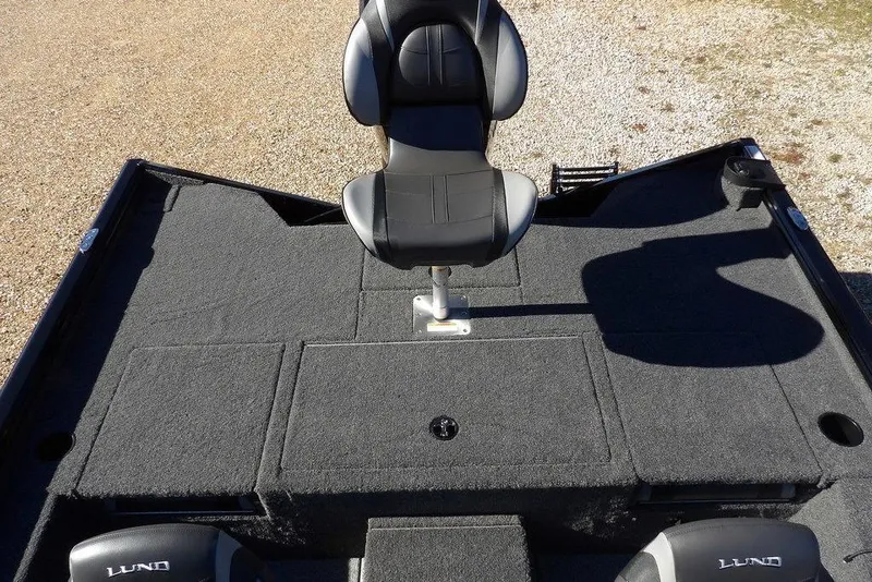 Slide: The Image of 2026 Lund 1875 Renegade boat deck with swivel seat, carpeted surface, and storage compartments. - 12