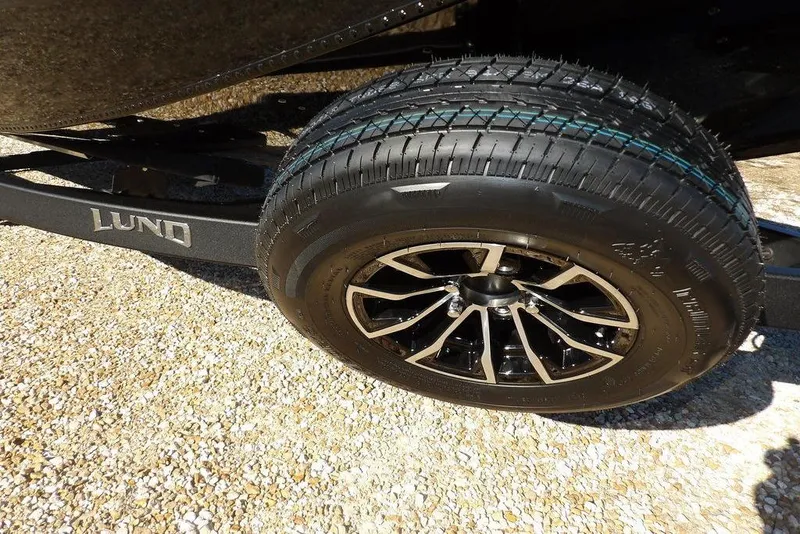 Slide: The Image of 2026 Lund 1875 Renegade trailer wheel on gravel surface. - 43