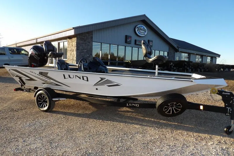 The Image of 2026 Lund 1875 Renegade boat on trailer outside dealership, sunny day. - 1