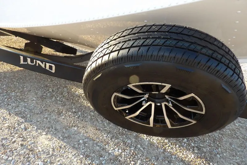 Slide: The Image of 2026 Lund 1875 Renegade trailer wheel on gravel surface. - 41