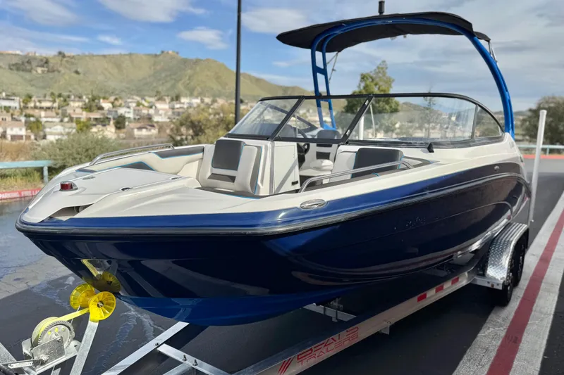 Slide: The Image of 2020 Yamaha Boats AR210 on trailer, sleek design, blue and white color scheme, scenic background. - 3