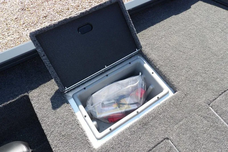 Slide: The Image of Open storage compartment in 2026 Crestliner XFC 189 boat, containing a plastic bag with items. - 11