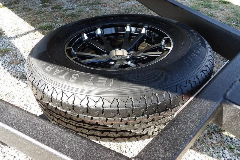 Slide: The Image of 2026 Crestliner XFC 189 trailer tire with black alloy wheel on gravel. - 32