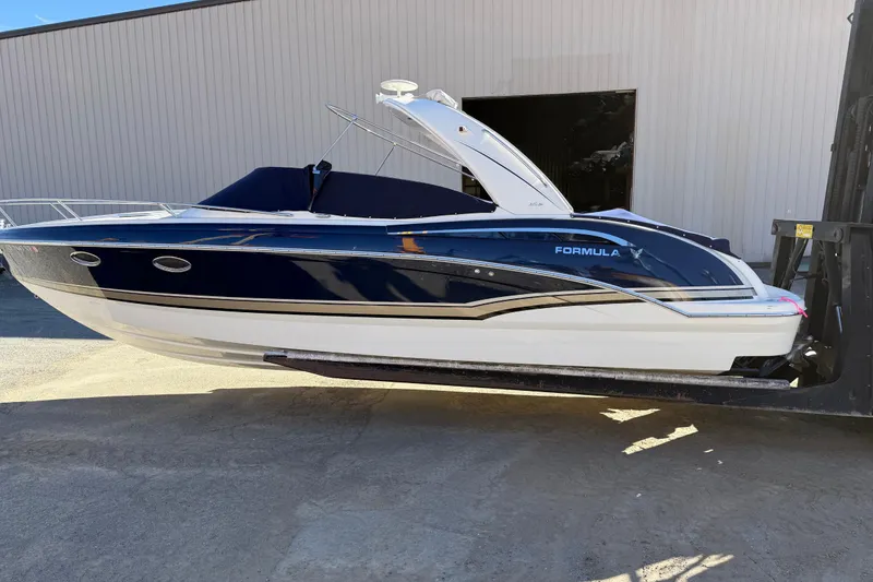 The Image of 2014 Formula 310 Sun Sport boat in blue and white, displayed on a lift. - 0