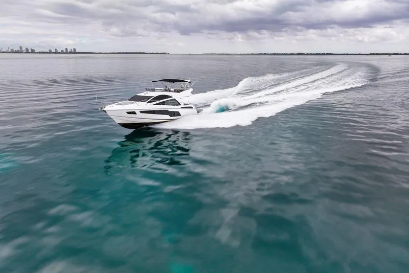 Slide: The Image of 2016 Sunseeker Manhattan 55 yacht cruising on open water under cloudy skies. - 11