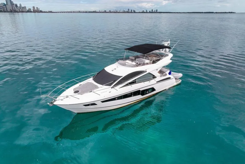 Slide: The Image of 2016 Sunseeker Manhattan 55 yacht on calm turquoise waters near city skyline. - 16