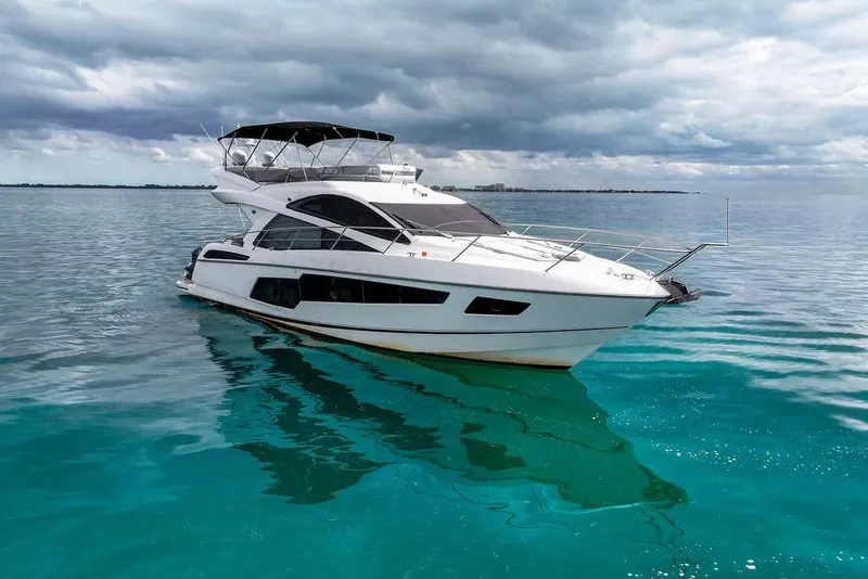 Slide: The Image of 2016 Sunseeker Manhattan 55 yacht on turquoise water under cloudy sky. - 4