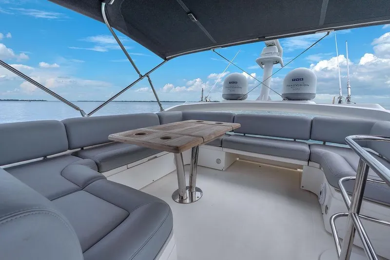 Slide: The Image of 2016 Sunseeker Manhattan 55 yacht deck with seating and table, under a clear blue sky. - 71