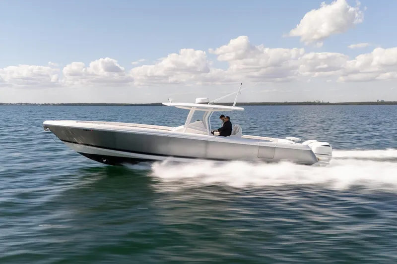 The Image of 2015 Intrepid 400 Center Console boat speeding on open water under a cloudy sky. - 0