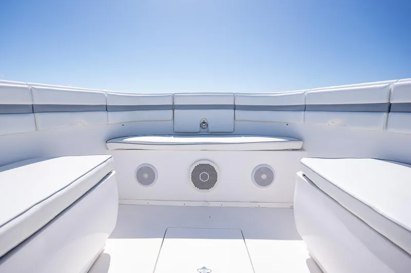 Slide: The Image of 2015 Intrepid 400 Center Console boat interior with cushioned seating and speakers under clear blue sky. - 16