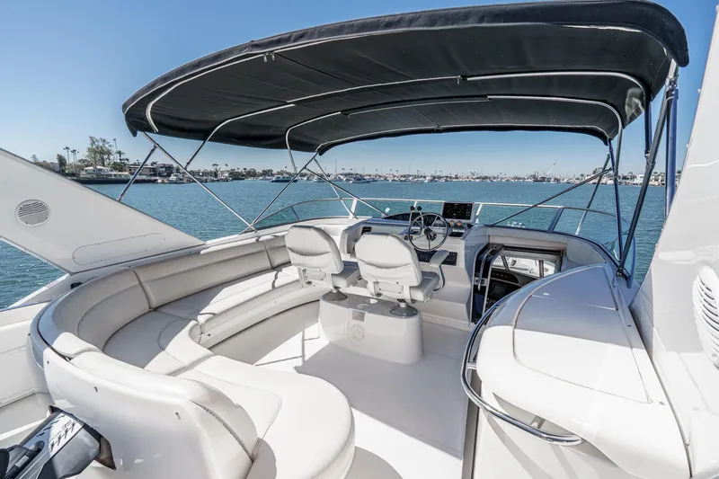 Slide: The Image of 2000 Bayliner 5788 Pilot House Motoryacht cockpit with seating, helm, and canopy on water. - 12