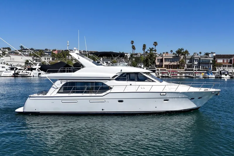Slide: The Image of 2000 Bayliner 5788 Pilot House Motoryacht cruising in a marina under clear blue skies. - 4