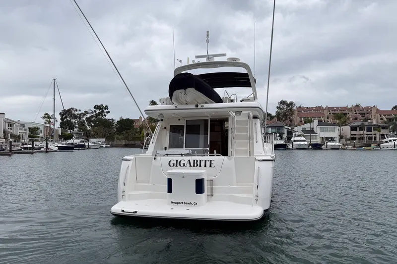 Slide: The Image of 2000 Bayliner 5788 Pilot House Motoryacht docked in a marina, overcast sky. - 5