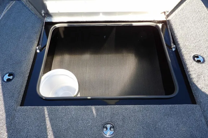 Slide: The Image of Open storage compartment in 2026 Crestliner XFC 189 boat, featuring a white bucket inside. - 19