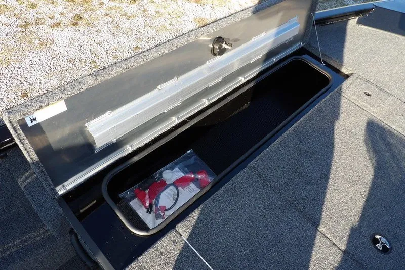 Slide: The Image of 2026 Crestliner XFC 189 boat storage compartment with accessories, open lid, and carpeted deck. - 27