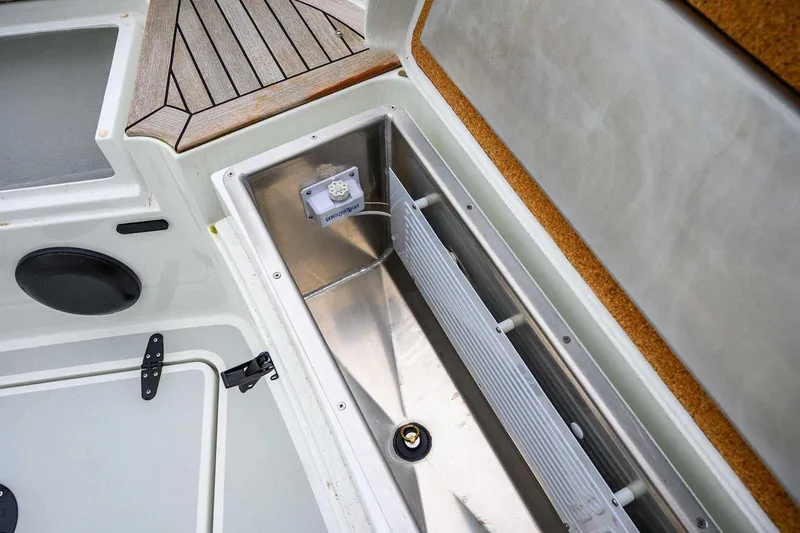 Slide: The Image of 2024 Targa 27.2 boat storage compartment with stainless steel interior and wooden deck detail. - 24