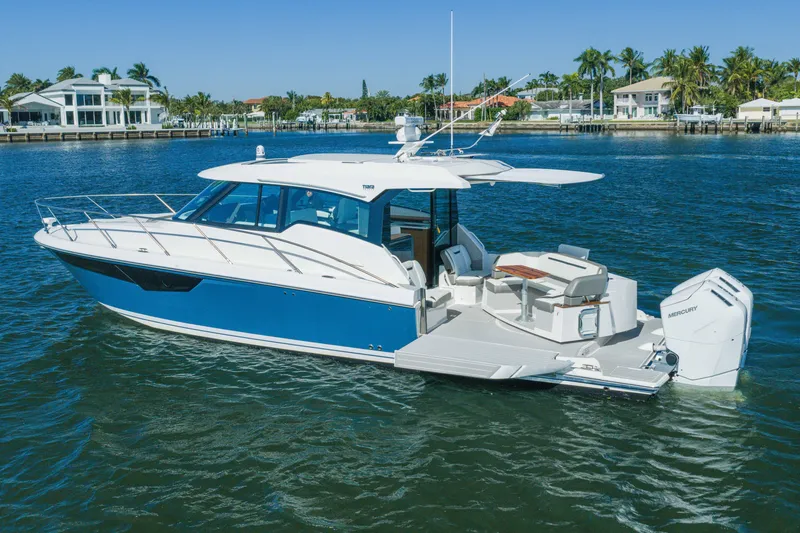 Slide: The Image of 2025 Tiara Yachts 43 LE cruising on a sunny day near waterfront homes. - 52