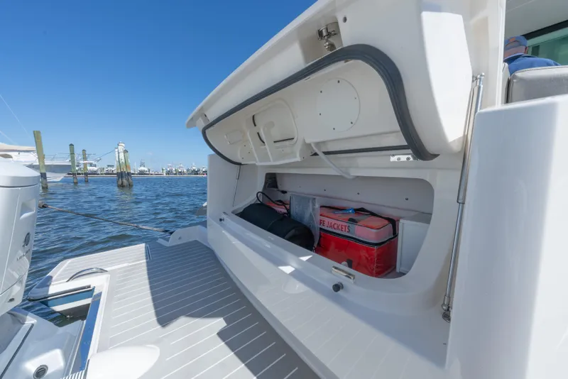 Slide: The Image of 2025 Tiara Yachts 43 LE storage compartment with life jackets, docked by the water. - 7